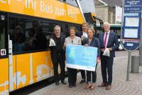 Vertreter verschiedener politischer Ebenen zeigen vor dem AirLiner-Bus das Kampagnen-Plakat "Bus bewegt besser".
